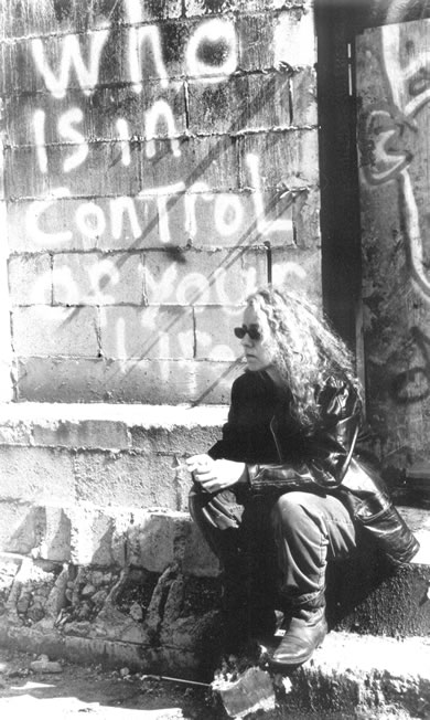 photo of Elaine sitting on steps in front of graffitti that says 'who is in control of your life'